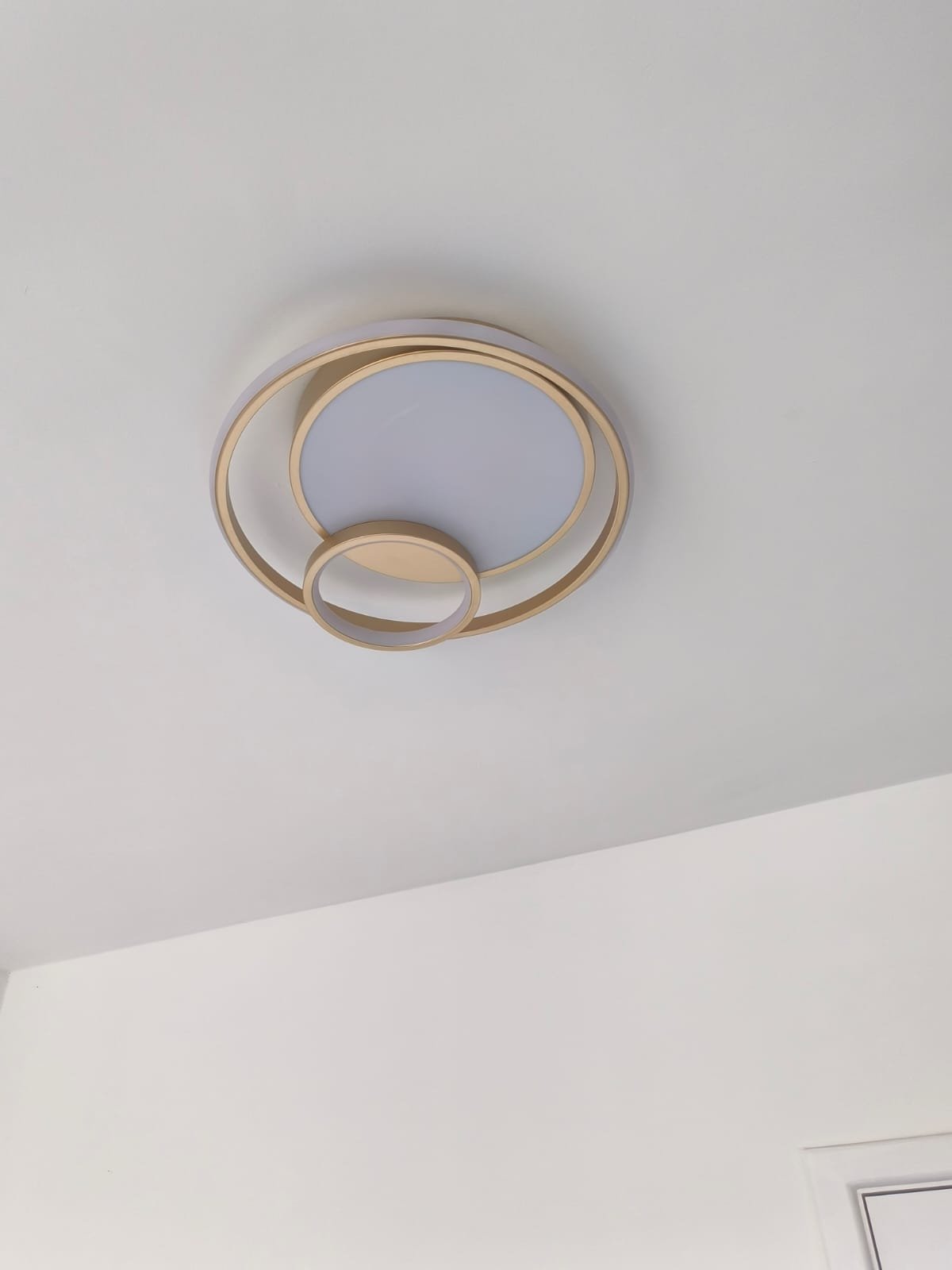 Plafon de LED com anéis dourados instalado no teto de um ambiente residencial