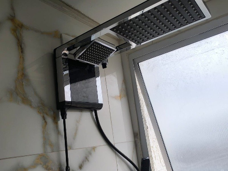 Chuveiro elétrico pressurizado moderno instalado em banheiro com fiação adequada e segura