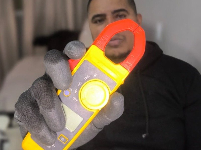 Eletricista profissional realizando medição e teste de corrente elétrica com alicate amperímetro digital