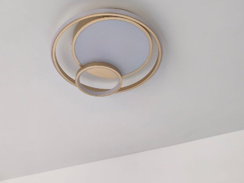 Plafon de LED com anéis dourados instalado no teto de um ambiente residencial